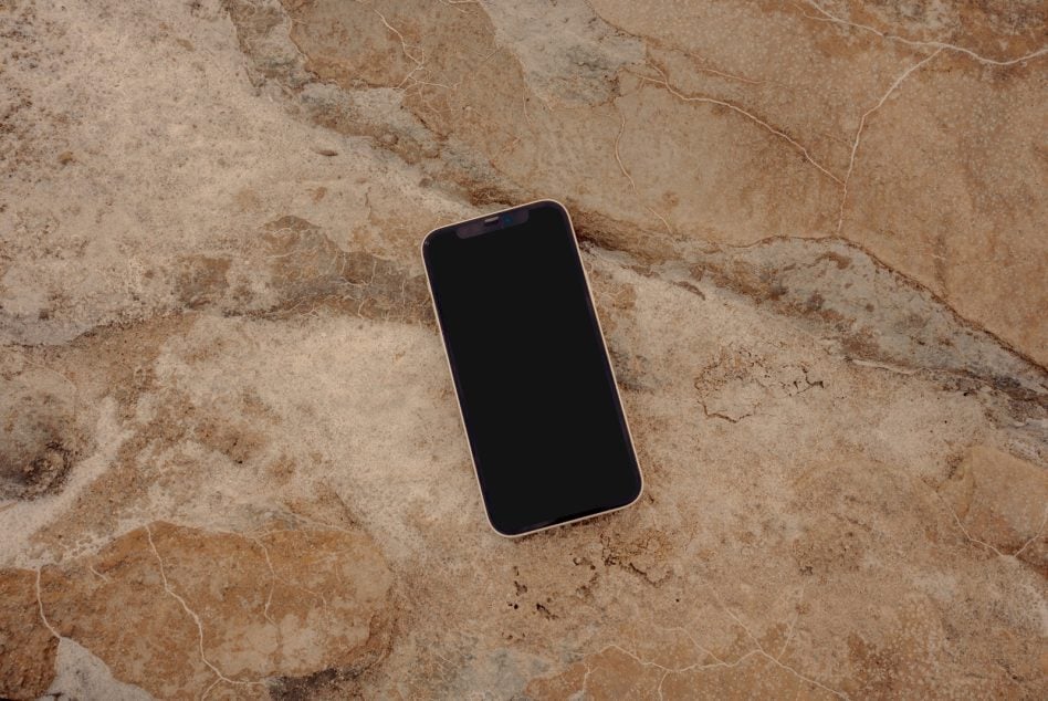 Device with blank screen resting on weathered beige stone texture